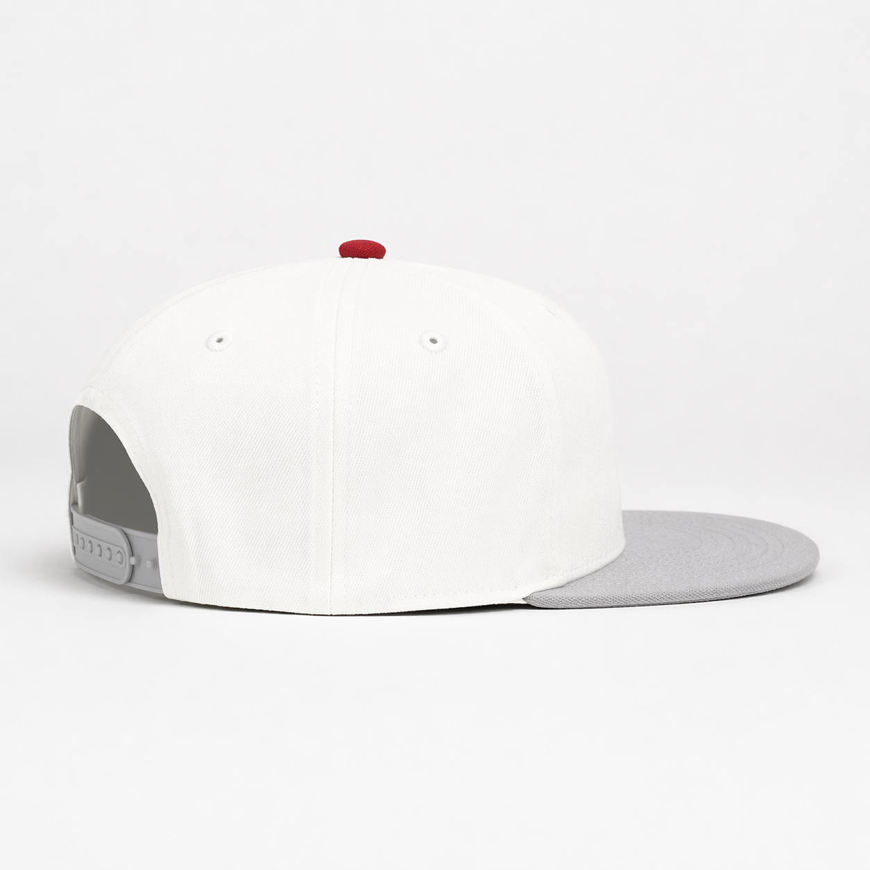 White snapback cap with grey brim, red top button, side view on white background