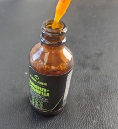 Supplement dropper bottle with orange liquid on black surface