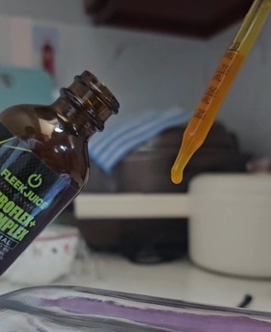 Close-up of supplement dropper and bottle with liquid in a kitchen setting